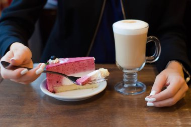 Genç güzel kadın tablo kek üzerine köpük sütlü kahve içer