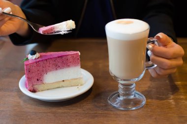 Genç güzel kadın tablo kek üzerine köpük sütlü kahve içer