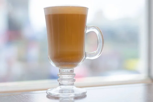Кофейный латте с пеной на окне стола — стоковое фото