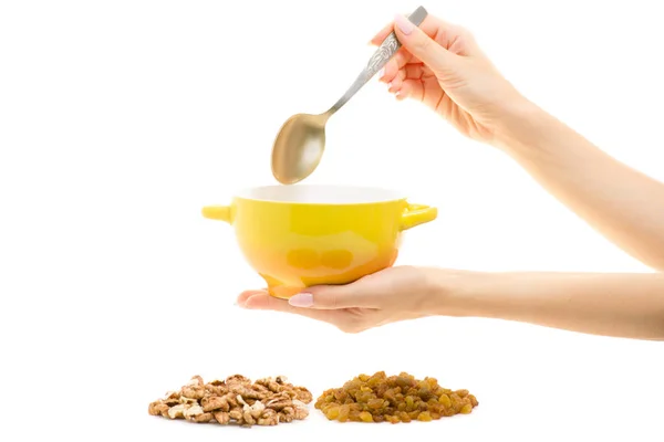 Mingau de cereal em uma chapa com uma colher em umas passas de mão femininas nozes — Fotografia de Stock