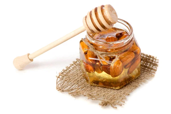 Un tarro de miel con una cuchara para almendras de nueces de miel — Foto de Stock