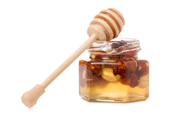 Un tarro de miel con una cuchara para nueces de miel — Foto de Stock