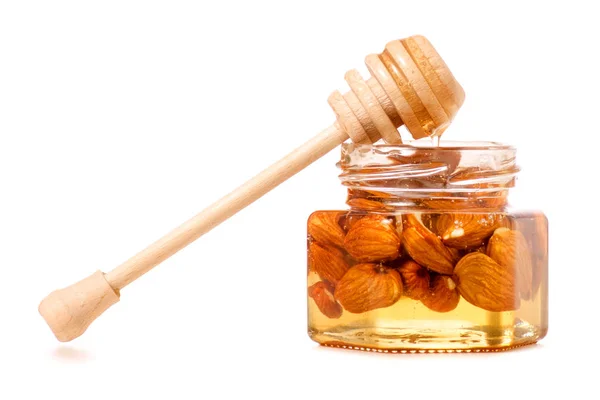 Um pote de mel com uma colher para amêndoas de nozes de mel — Fotografia de Stock