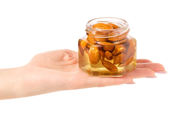 En honung burk med nötter mandel i händer — Stockfoto