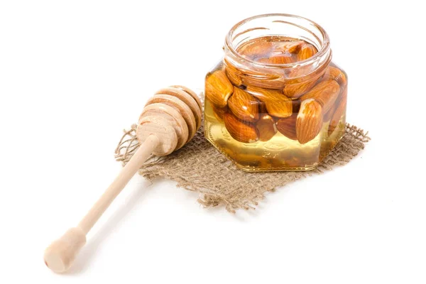 Un tarro de miel con una cuchara para almendras de nueces de miel — Foto de Stock
