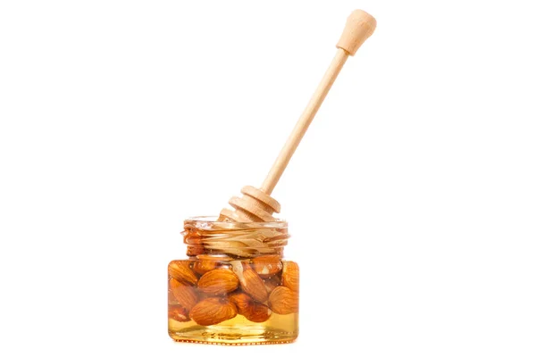 Un tarro de miel con una cuchara para almendras de nueces de miel — Foto de Stock