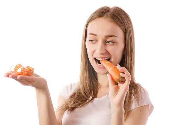 Schöne junge lächelnde Frau hält eine Karotte und misst Zentimeter in den Händen — Stockfoto