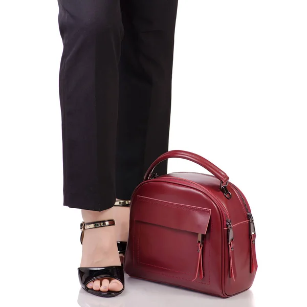 Женские ноги в классических черных брюках черные лаковые туфли с красной кожаной сумочкой в руке — стоковое фото