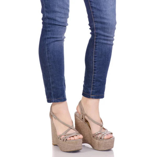 Vrouwelijke benen in jeans en grijze sandalen op een wig — Stockfoto