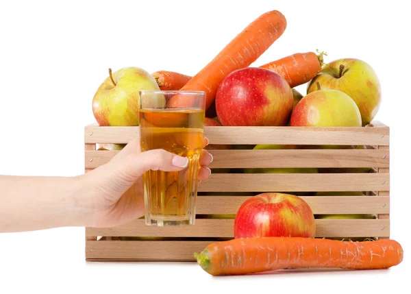 Caja de madera de manzanas zanahorias vaso de jugo en la mano — Foto de Stock