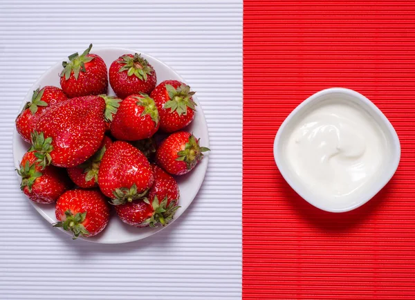 Aardbei op plaat crème op rood witte achtergrond — Stockfoto