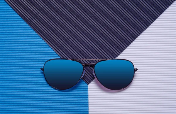 Niebieskie okulary na niebieskim tle, widok z góry. — Zdjęcie stockowe