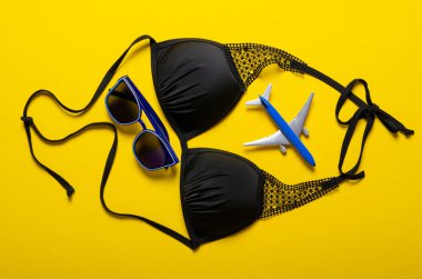 Sarı arka planda, kameralı, güneş gözlüklü, mayolu düz gezgin aksesuarları.