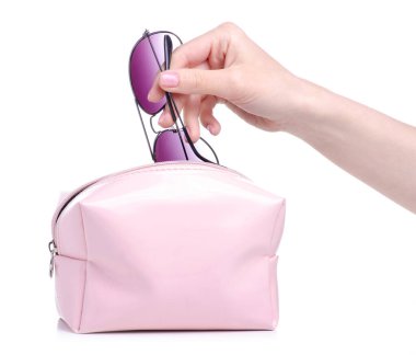 Güneş gözlüklerini pembe makyaj çantasına koy.