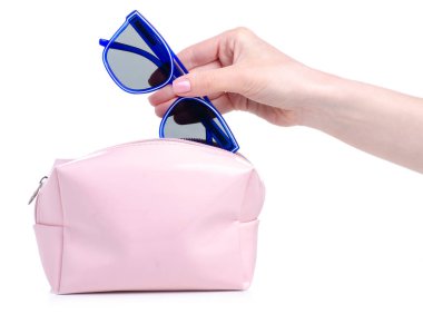 Mavi güneş gözlüklerini pembe makyaj çantasına koy.