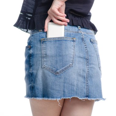 Kadın cep telefonunu kot etek cebine koyuyor.