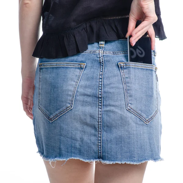 Mulher coloca telefone celular no bolso saia jeans — Fotografia de Stock