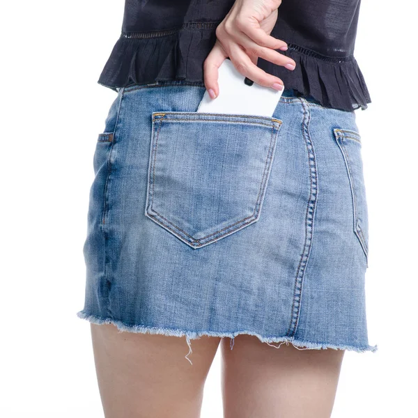Женщина кладет мобильный телефон в джинсовый карман юбки — стоковое фото