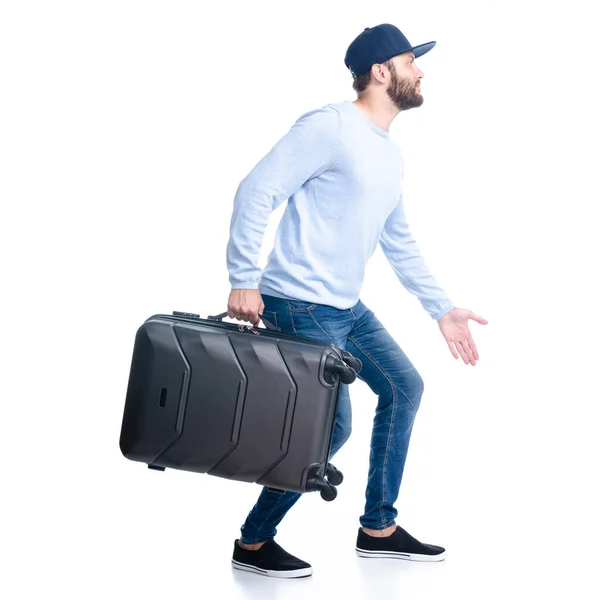 Мужчина в джинсах, держащий чемодан, идет пешком — стоковое фото