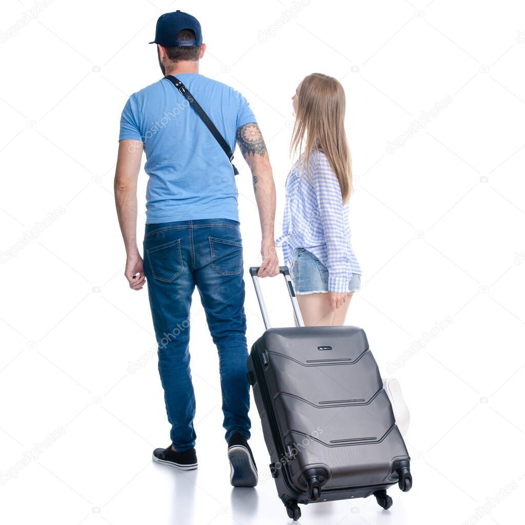 happy couple of tourists with black suitcase luggages smiling goes walking