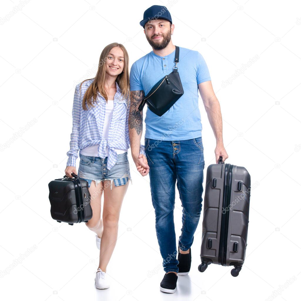 happy couple of tourists with black suitcase luggages smiling goes walking
