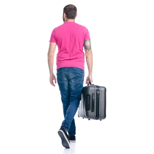 Hombre en jeans sosteniendo viaje maleta caminando va — Foto de Stock