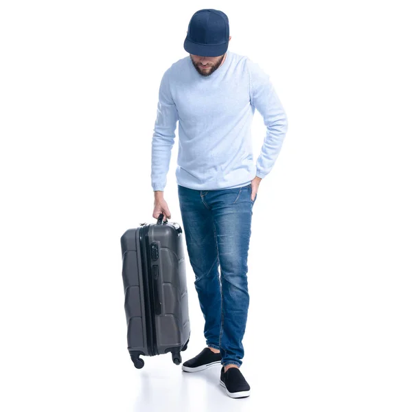 Mężczyzna w dżinsach trzyma walizkę na stojąco. — Zdjęcie stockowe