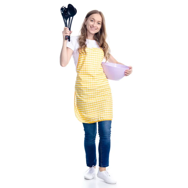 Жінка в жовтому фартусі з кухонною чашею та посудом в руці — стокове фото