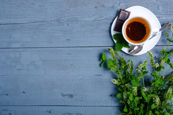 Cangkir teh mint putih dengan lemon dan coklat dengan latar belakang kayu abu-abu biru — Stok Foto