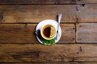 Kahverengi ahşap arka planda limon ve çikolatalı beyaz nane çayı.