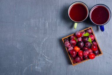 Kupa koyu renkli taş masa arkaplanındaki erikleri sıkıştırır