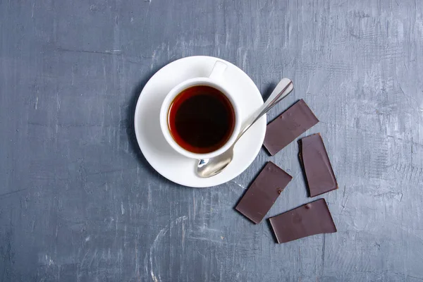 灰色の暗い石のテーブルの背景にチョコレートとお茶の白いカップ — ストック写真