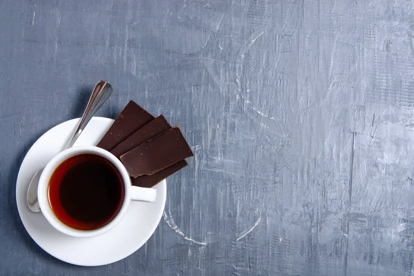 Weiße Tasse Tee mit Schokolade auf grauem dunklem Stein Tischhintergrund — Stockfoto