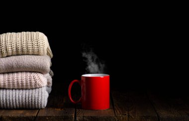 Bir fincan çay, kahve ve örgü kıyafetlerden oluşan bir yığın.