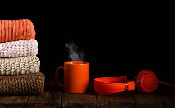Стопка одежды из трикотажа с чашкой чая, кофе, наушниками — стоковое фото