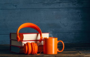 Modern kulaklıklar, yığınla kitap ve bir fincan çay fincanı.