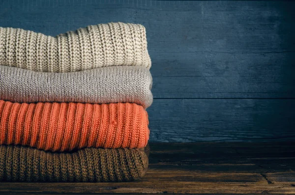 Pile pliée de vêtements chauds tricotés sur fond en bois, pulls, tricots — Photo