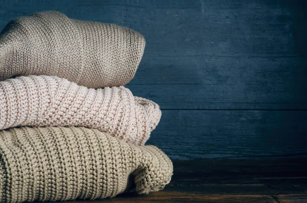 Pile pliée de vêtements chauds tricotés sur fond en bois, pulls, tricots — Photo