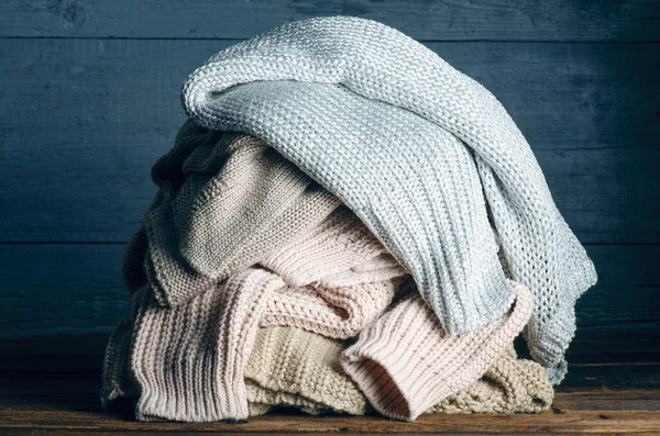 Pile de vêtements chauds tricotés sur fond bois, pulls, tricots — Photo
