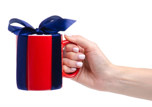Red cup mug with blue ribbon bow gift in hand — Stock Photo, Image