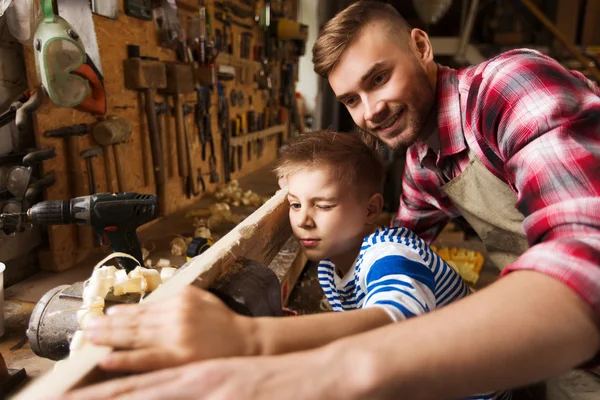 Ο πατέρας και ο μικρός γιος με ξύλινη σανίδα στο εργαστήριο — Φωτογραφία Αρχείου