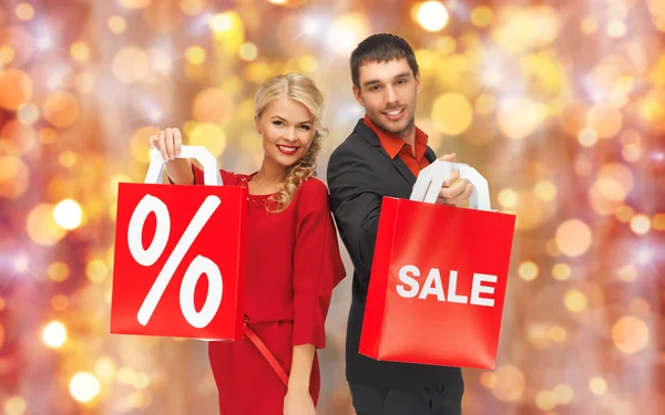 Casal com sinal de venda em sacos de compras — Fotografia de Stock