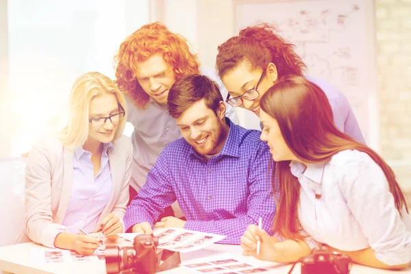 Equipo sonriente con cámara fotográfica e imágenes en la oficina — Foto de Stock