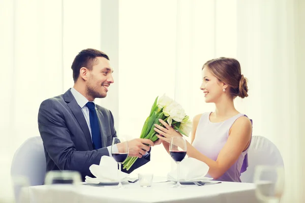 Homme souriant donnant bouquet de fleurs au restaurant — Photo