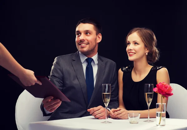 Waiter giving menu to happy couple at restaurant — Stock Photo, Image