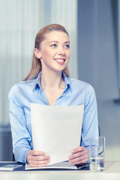 Lachende vrouw bedrijf documenten in office — Stockfoto