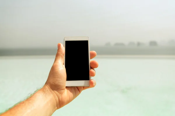 Primo piano di smartphone mano maschile tenuta sulla spiaggia — Foto Stock