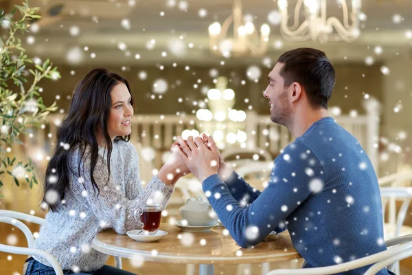 Happy couple with tea holding hands at restaurant — Stock Photo, Image