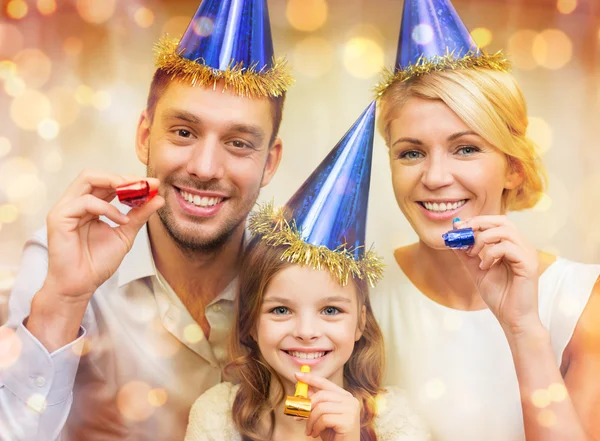 Sonriente familia en sombreros azules soplando cuernos favor — Foto de Stock
