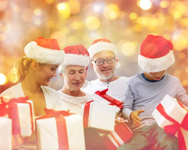 Happy family in santa hats with gift boxes — Stock Photo, Image